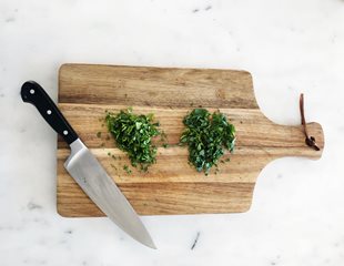 Chopped up herbs on a cutting board to be used in recipes 
