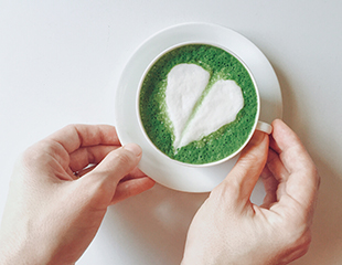 Cup of matcha green tea, decorated with a white foam heart
