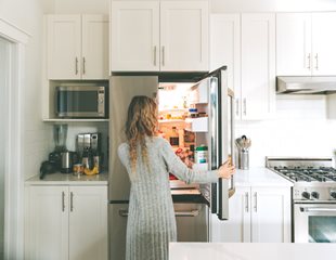 Woman standing in front of open refrigerator door