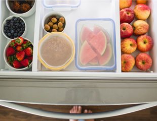 Various fruits in different containers organized in a freezer