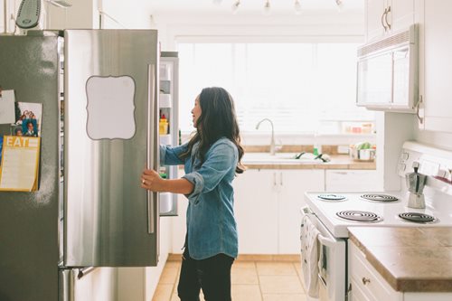 Woman standing in front of open refrigerator door 