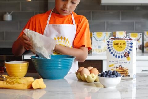 Michelle's son pouring Simple Mills pancake and waffle mix into mixing bowl