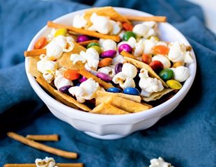 Bowl of popcorn, pretzels, assorted chocolates and Simple Mills Fine Ground Sea Salt Crackers