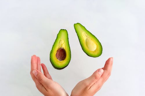 Person hands avocado cut in half