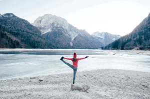 Woman doing a yoga pose in front of a lake with mountain in the background