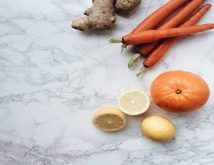 White marble countertop displaying Oranges, Ginger, Lemons and carrots