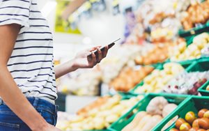 Shopper on phone in store, researching food for recipes