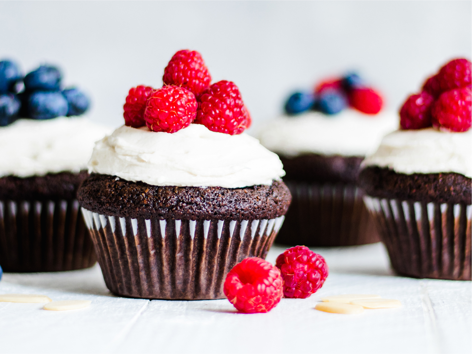 Chocolate cupcakes with white frosting, blueberries and rasberries on top